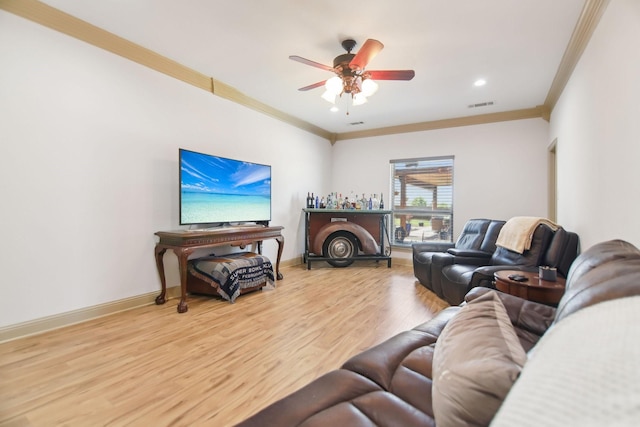 living room with crown molding, visible vents, baseboards, wood finished floors, and a ceiling fan