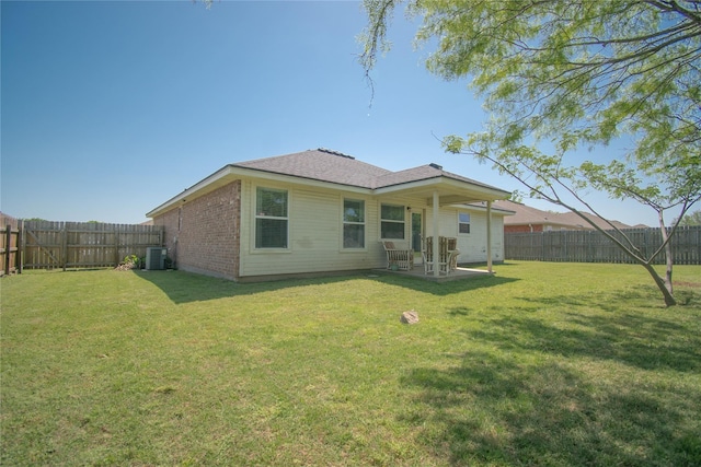 rear view of property featuring a lawn, a fenced backyard, and central AC unit
