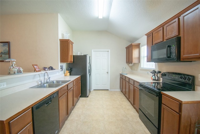 kitchen with a sink, brown cabinetry, black appliances, light countertops, and lofted ceiling