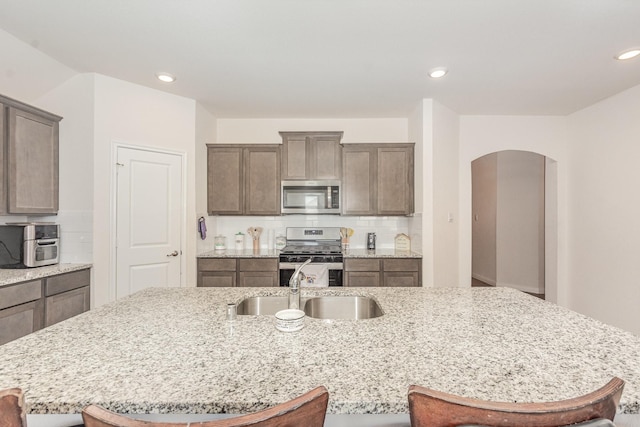 1607 Grand Villa St, Princeton, TX 75407 - kitchen with arched walkways, appliances with stainless steel finishes, a sink, and a breakfast bar