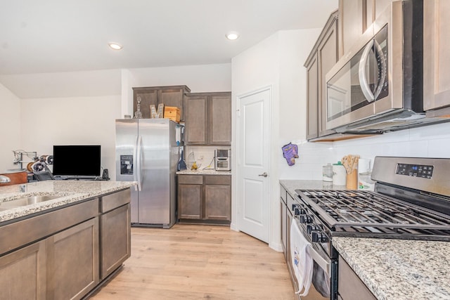 1607 Grand Villa St, Princeton, TX 75407 - kitchen featuring light stone counters, a sink, light wood-type flooring, stainless steel appliances, and backsplash