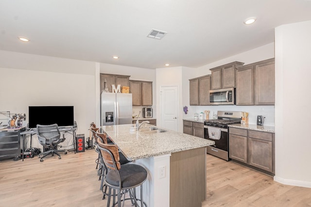 1607 Grand Villa St, Princeton, TX 75407 - kitchen with light wood finished floors, stainless steel appliances, a breakfast bar, visible vents, and a sink