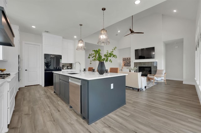 4330 Silver Spur Dr, Prosper, TX 75078 - kitchen featuring stainless steel appliances, a ceiling fan, white cabinets, a tiled fireplace, and under cabinet range hood