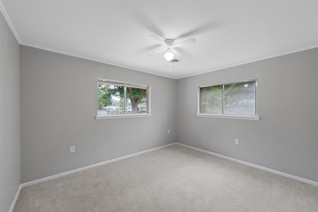 carpeted empty room with baseboards, ceiling fan, and crown molding
