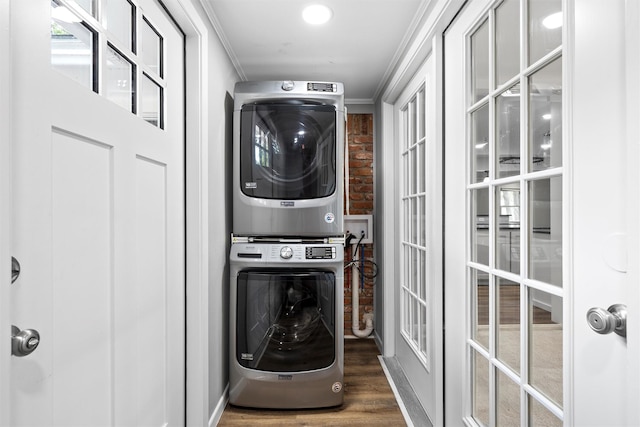 laundry room with french doors, wood finished floors, crown molding, stacked washing maching and dryer, and laundry area