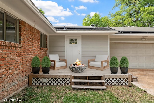 doorway to property featuring a garage, solar panels, brick siding, and a wooden deck