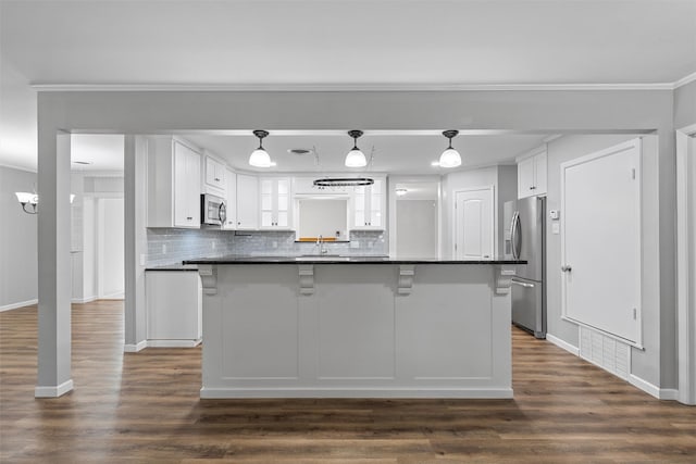 kitchen featuring dark countertops, backsplash, white cabinetry, and appliances with stainless steel finishes