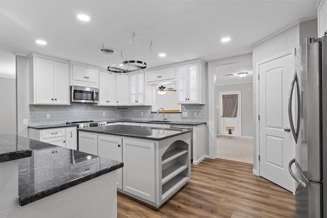 kitchen featuring a sink, backsplash, white cabinetry, a kitchen island, and appliances with stainless steel finishes