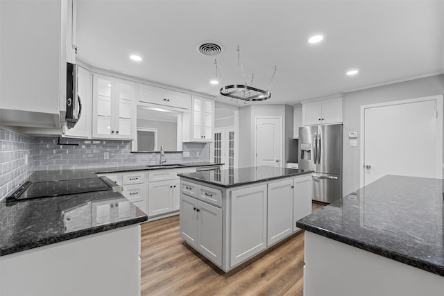 kitchen featuring backsplash, stainless steel refrigerator with ice dispenser, a sink, and a kitchen island