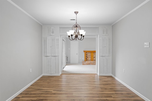 unfurnished dining area featuring an inviting chandelier, crown molding, and wood finished floors