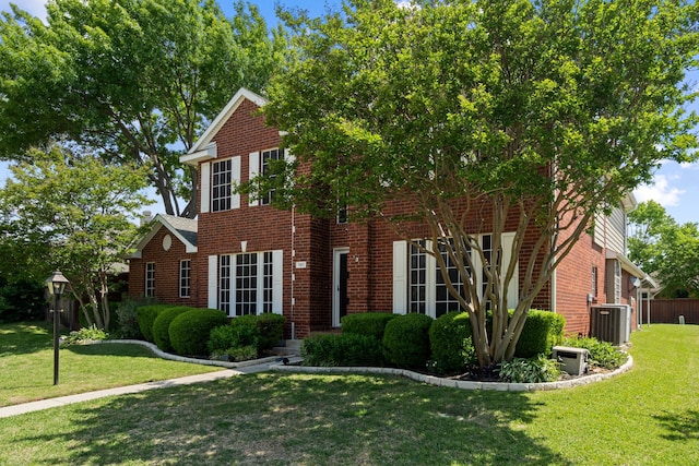 colonial home featuring brick siding, central AC, a front lawn, and fence