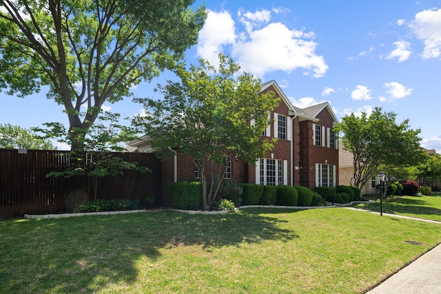 view of front of home with brick siding, a front lawn, and fence