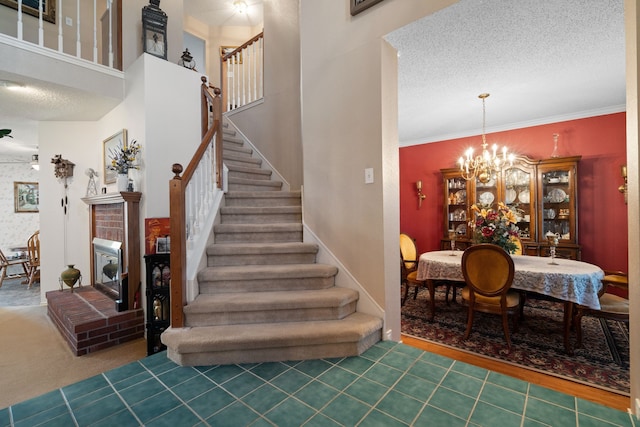 stairway with a fireplace, a textured ceiling, tile patterned floors, and an inviting chandelier