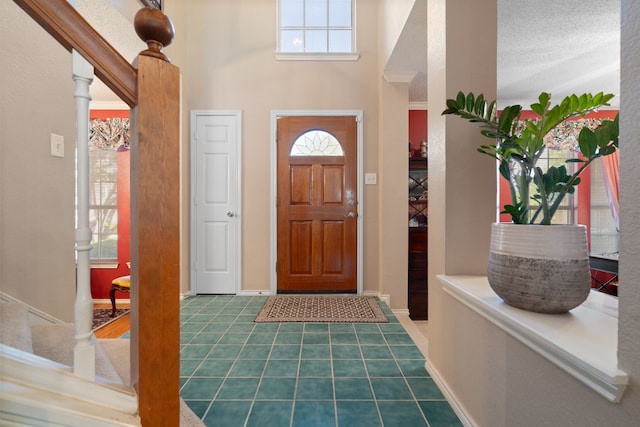 foyer with tile patterned flooring, baseboards, and a towering ceiling