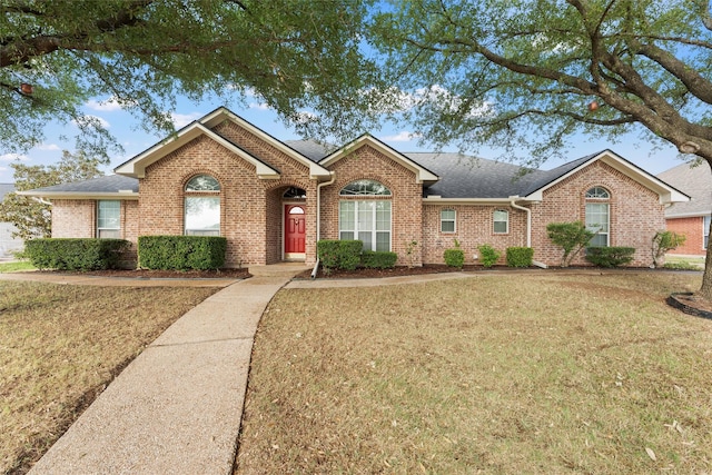 ranch-style house featuring a front lawn, brick siding, and roof with shingles