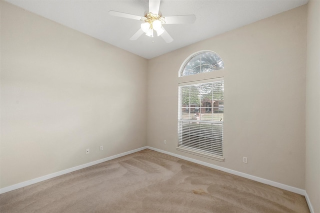 spare room with ceiling fan, light carpet, and baseboards