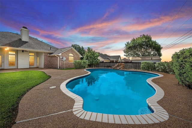 pool at dusk with a fenced backyard, a patio, a fenced in pool, and a lawn