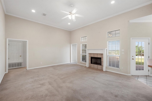 unfurnished living room with a high ceiling, a ceiling fan, ornamental molding, light carpet, and baseboards