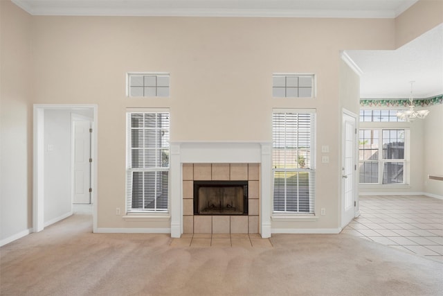 unfurnished living room with carpet floors, crown molding, baseboards, a chandelier, and a tiled fireplace