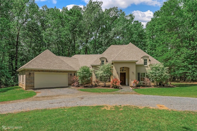 french country inspired facade featuring stucco siding, gravel driveway, a front lawn, and a garage