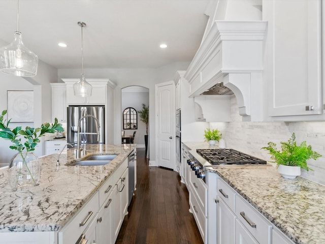kitchen with white cabinets, stainless steel appliances, arched walkways, and a sink