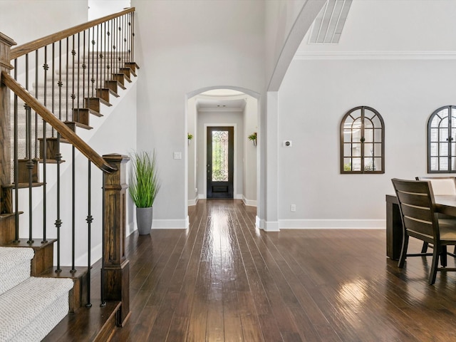 foyer with visible vents, arched walkways, baseboards, and dark wood-style flooring