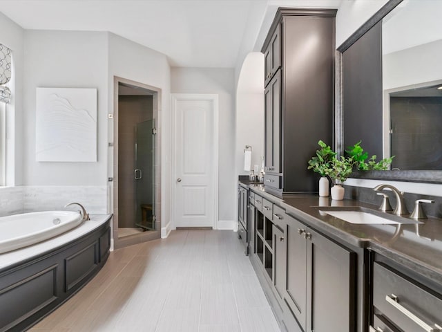 bathroom with a garden tub, double vanity, baseboards, a sink, and a stall shower