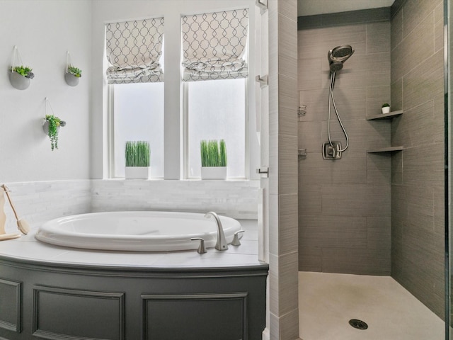 bathroom featuring a healthy amount of sunlight, tiled shower, and a garden tub