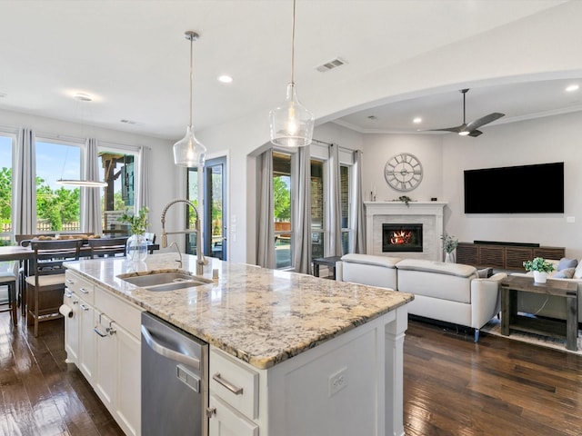 kitchen with visible vents, stainless steel dishwasher, a fireplace, a sink, and light stone counters