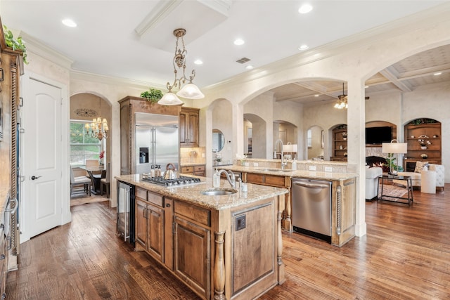 kitchen featuring an island with sink, a sink, appliances with stainless steel finishes, and brown cabinets