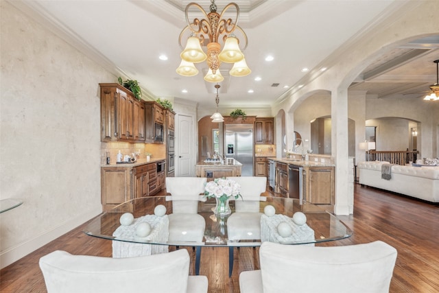 dining room with arched walkways, ceiling fan with notable chandelier, recessed lighting, dark wood-type flooring, and ornamental molding