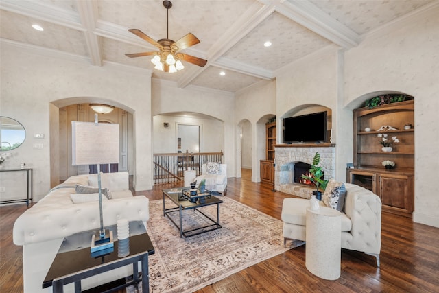 living area featuring ceiling fan, arched walkways, wood finished floors, beamed ceiling, and coffered ceiling
