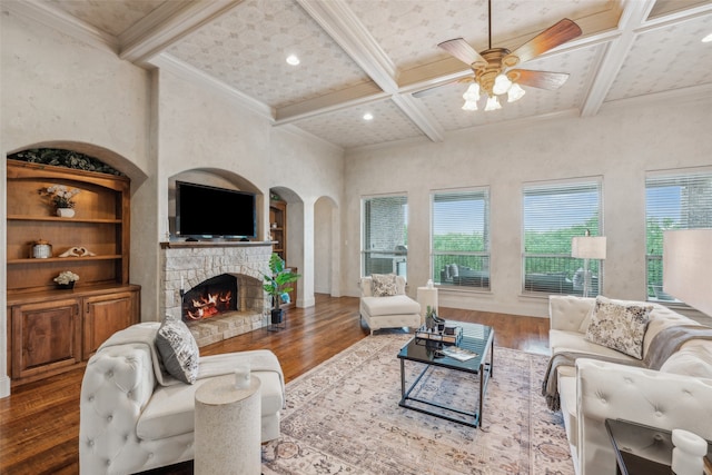 living area with ceiling fan, beam ceiling, arched walkways, wood finished floors, and coffered ceiling