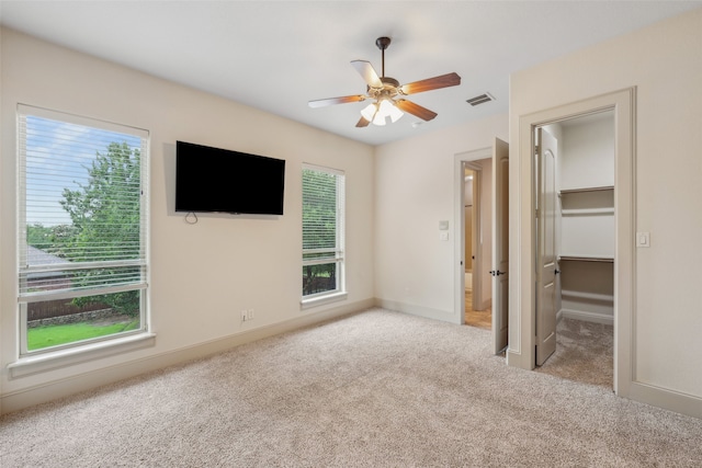 unfurnished bedroom with carpet floors, visible vents, baseboards, ceiling fan, and a spacious closet