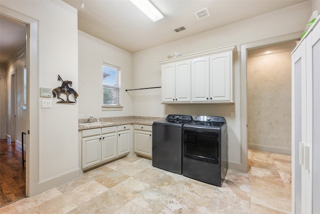 laundry area featuring visible vents, washing machine and dryer, baseboards, a sink, and cabinet space