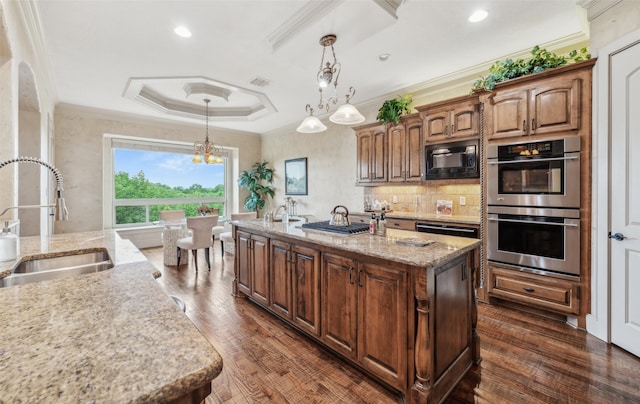 kitchen with black microwave, a sink, double oven, a kitchen island with sink, and visible vents