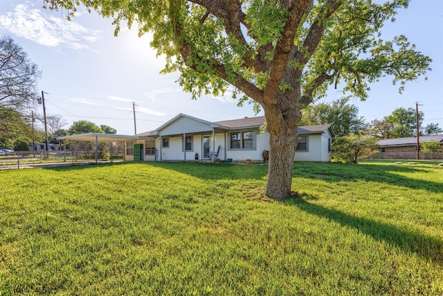 back of house with a carport, fence, and a yard