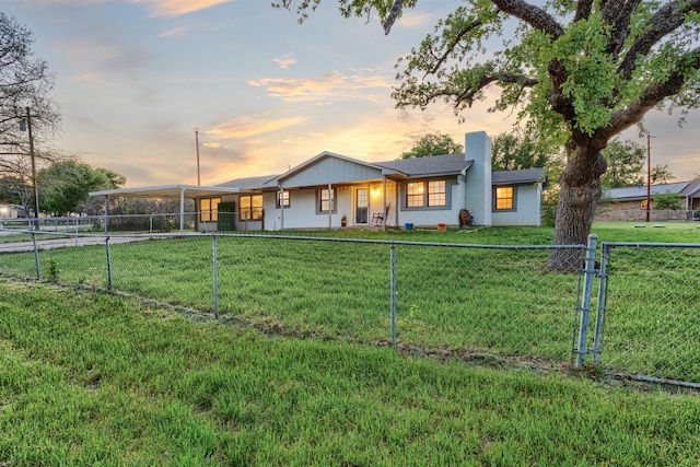 view of front of home with a fenced backyard, an attached carport, driveway, a chimney, and a lawn