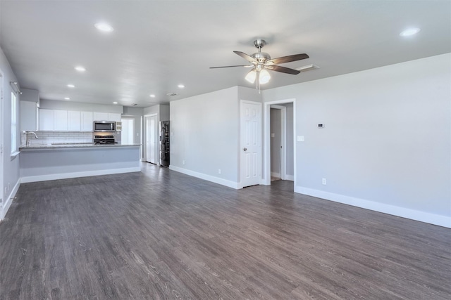 unfurnished living room with a ceiling fan, a sink, baseboards, dark wood-type flooring, and recessed lighting