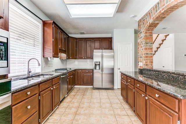kitchen featuring a sink, dark stone countertops, appliances with stainless steel finishes, and light tile patterned floors