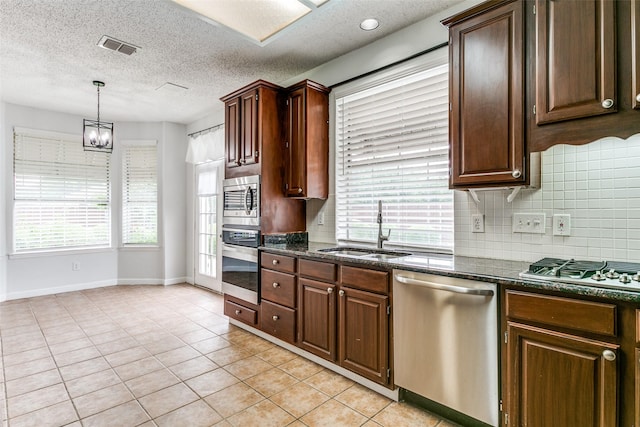 kitchen with backsplash, appliances with stainless steel finishes, a sink, baseboards, and light tile patterned flooring