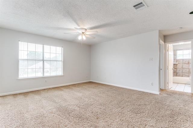 unfurnished room featuring light carpet, a textured ceiling, a ceiling fan, baseboards, and visible vents