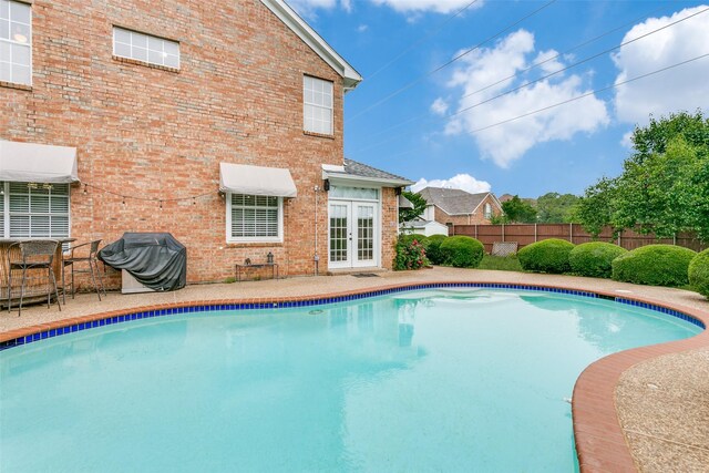 view of swimming pool with area for grilling, a fenced in pool, a fenced backyard, a patio area, and french doors