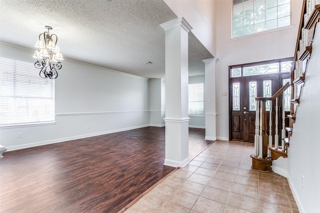 foyer entrance with ornamental molding, decorative columns, stairway, a textured ceiling, and light wood-style flooring