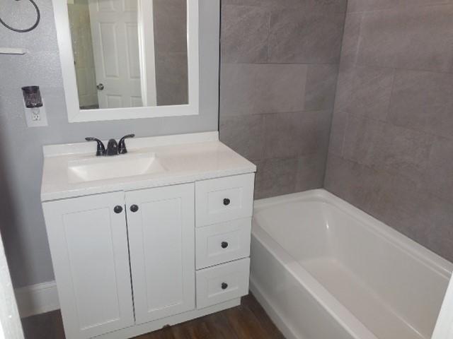 bathroom with a washtub, vanity, and wood finished floors