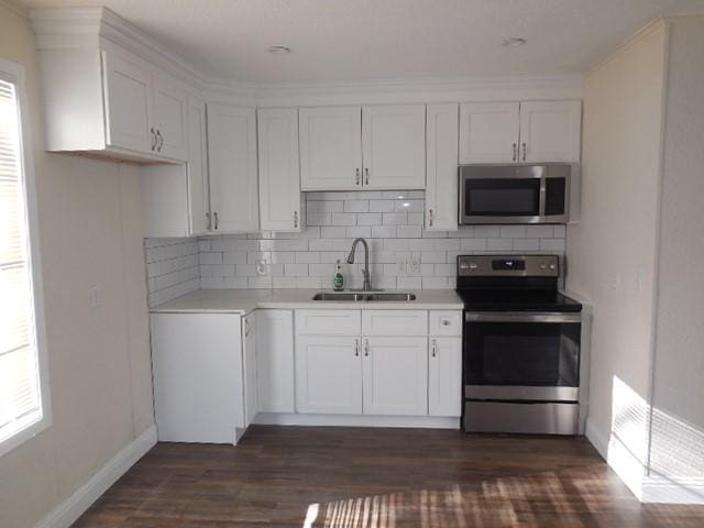 kitchen with white cabinets, decorative backsplash, appliances with stainless steel finishes, and a sink