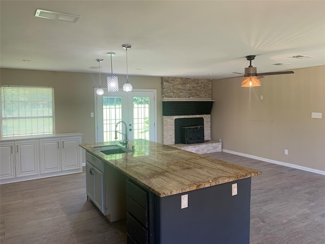 kitchen with french doors, a sink, a center island with sink, visible vents, and wood finished floors