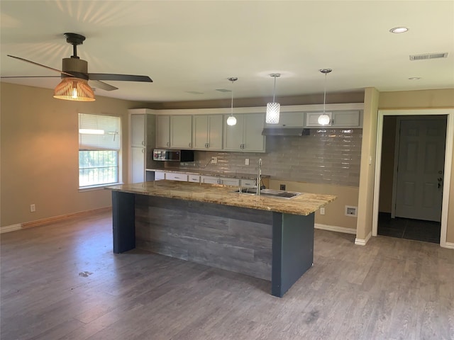 kitchen with stainless steel microwave, baseboards, visible vents, decorative backsplash, and light stone counters