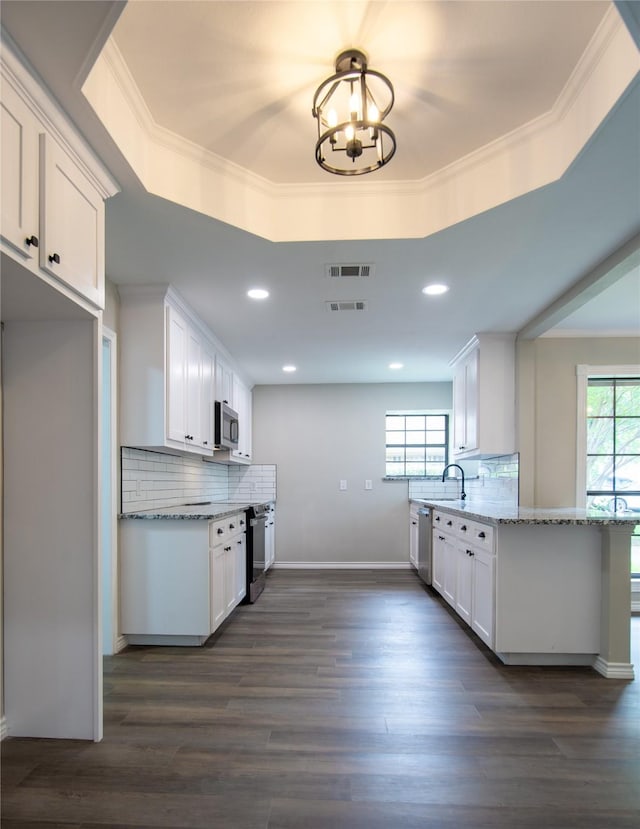 kitchen with white cabinets, stainless steel microwave, visible vents, a chandelier, and light stone countertops