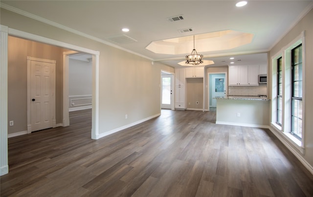unfurnished living room with plenty of natural light, a notable chandelier, visible vents, and a raised ceiling